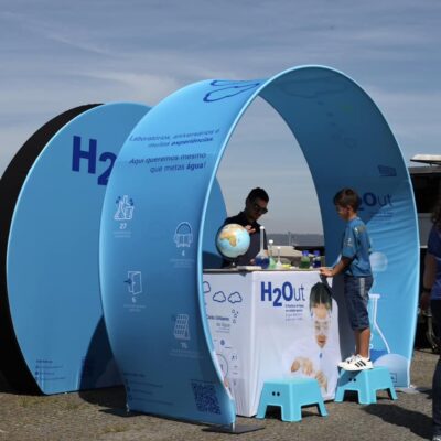 Stand personalizado com parede Tex Wave Wall 3D Moon da Poster Digital para o Pavilhão da Água, no evento no Porto, destacando produtos ecológicos.